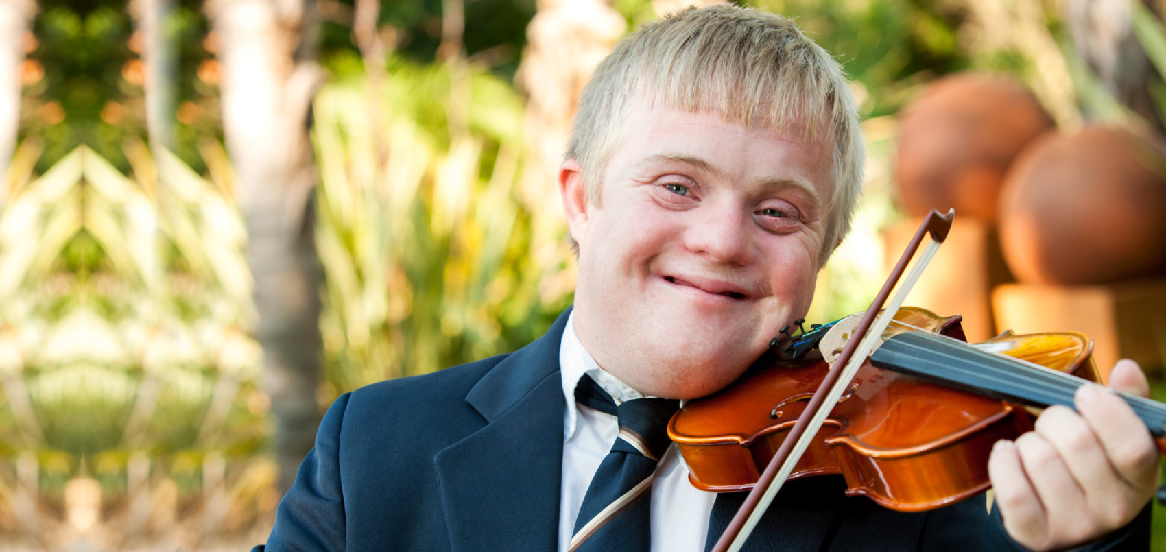 friendly handicapped boy playing violin outdoors