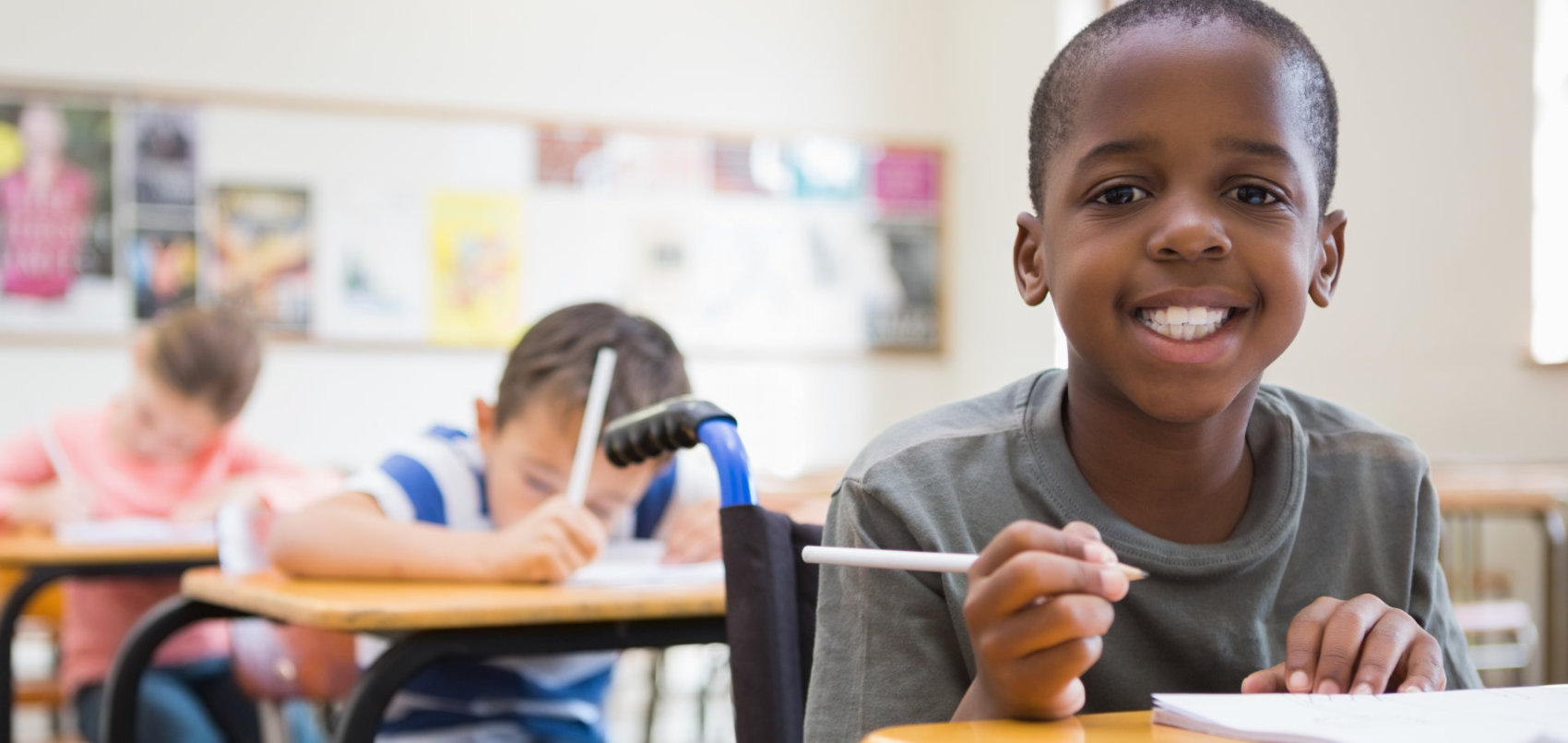 a boy holding a pencil and smiling