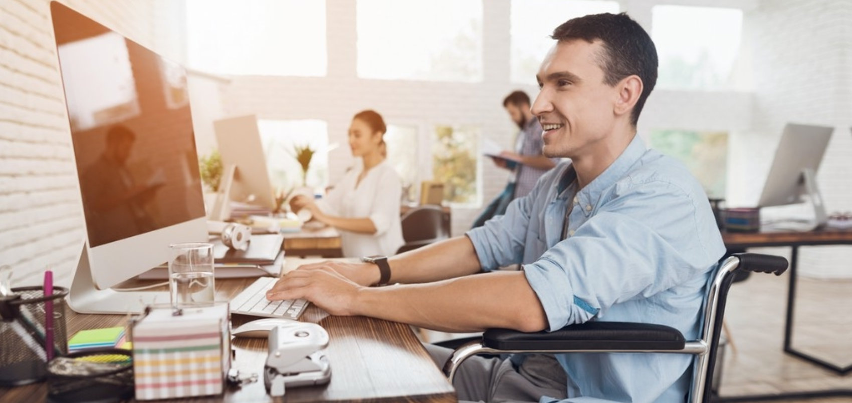 adult man in the wheelchair works in the office at the computer